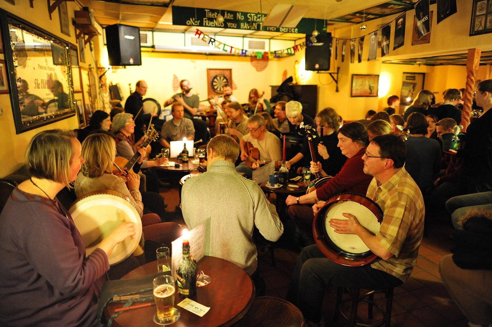 Musicians playing a traditional Irish music session in a warm, crowded pub